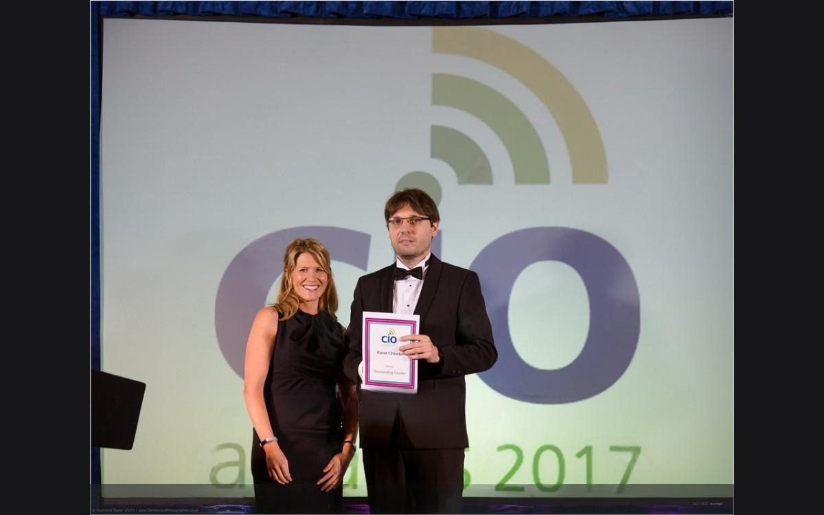 Karol Chlasta on stage holding his certificate beside the host, in front of a screen reading CIO awards 2017